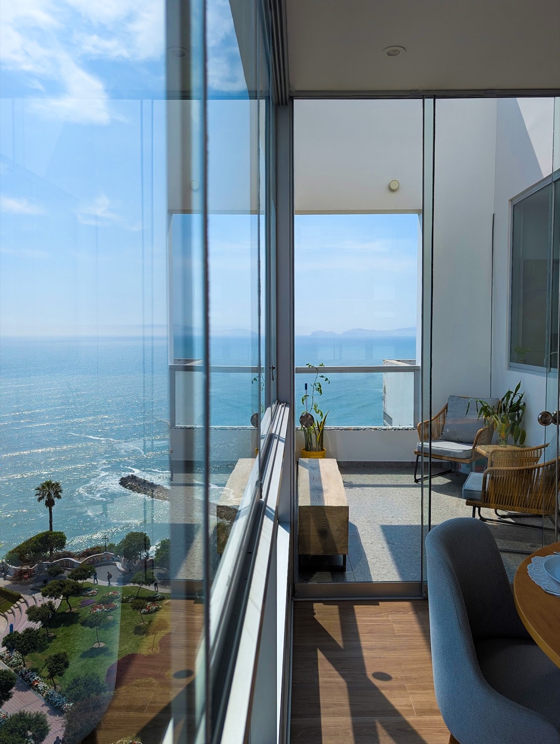 Floor-to-ceiling glass framing the ocean and the cliffside park